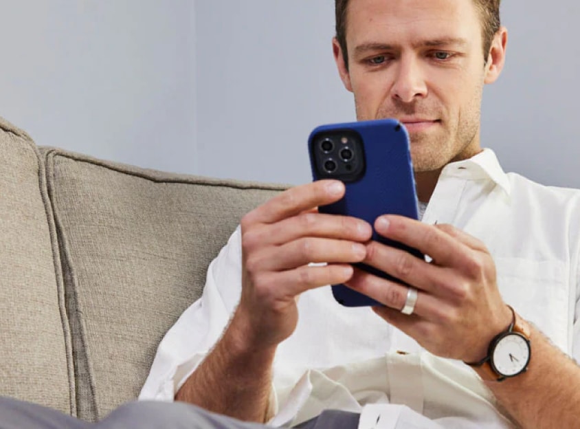 Bărbat pe canapea, uitându-se la telefon