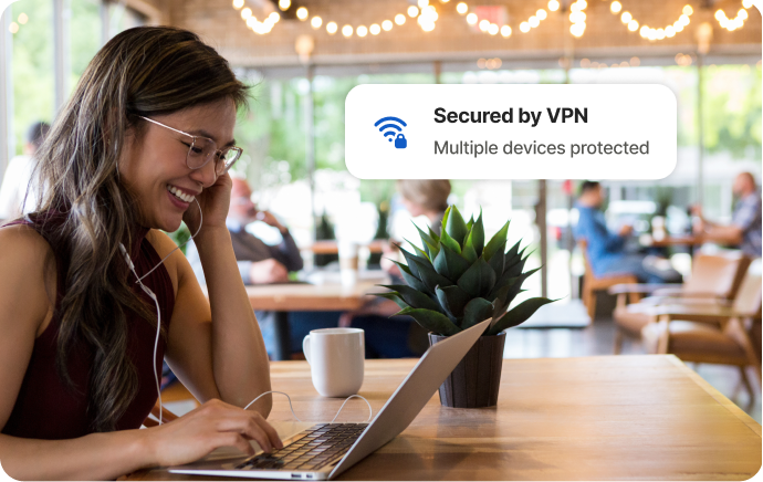 Femeie într-o cafenea râzând în fața ecranului unui laptop